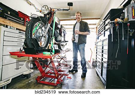 Caucasian man drinking coffee while repairing motorcycle in garage View Large Photo Image Stock Photo - Caucasian man drinking coffee while repairing motorcycle in garage. Fotosearch
