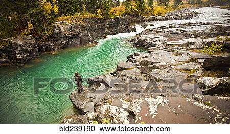 Stock Image - Caucasian man fishing at river. Fotosearch