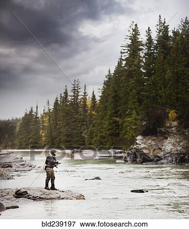 Stock Photo - Caucasian man fishing at river. Fotosearch