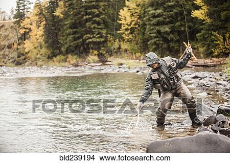 Picture - Caucasian man fishing in river holding net. Fotosearch