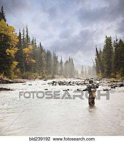Stock Image - Caucasian man fishing in river. Fotosearch