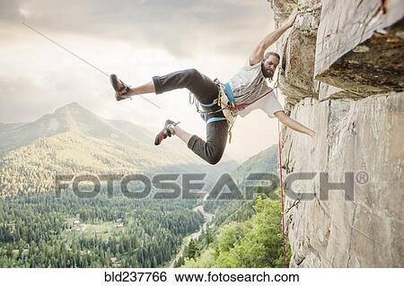 Caucasian man hanging from rock while climbing View Large Photo Image Stock Photograph - Caucasian man hanging from rock while climbing. Fotosearch