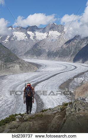Stock Photo - Caucasian man hiking in snowy mountains. Fotosearch