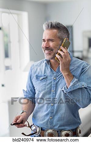 Caucasian man holding eyeglasses talking on cell phone View Large Photo Image Picture - Caucasian man holding eyeglasses talking on cell phone. Fotosearch