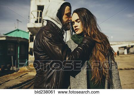 Stock Image - Caucasian man hugging woman outdoors. Fotosearch