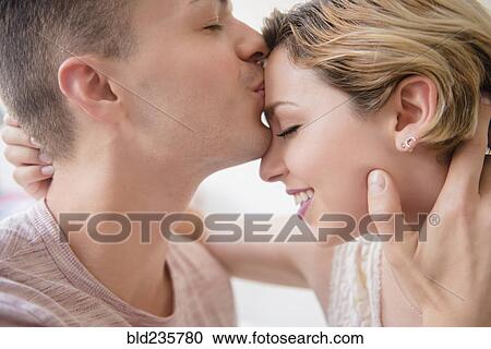 Stock Image - Caucasian man kissing girlfriend on forehead. Fotosearch