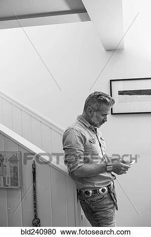 Caucasian man leaning on staircase bannister texting on cell phone View Large Photo Image Stock Image - Caucasian man leaning on staircase bannister texting on cell phone. Fotosearch