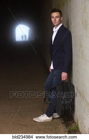 Picture - Caucasian man leaning on wall in tunnel. Fotosearch