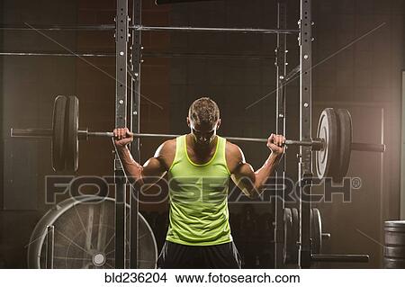 Caucasian man lifting barbell in gymnasium View Large Photo Image Picture - Caucasian man lifting barbell in gymnasium. Fotosearch