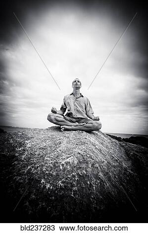 Caucasian man meditating on rocks at ocean View Large Photo Image Stock Image - Caucasian man meditating on rocks at ocean. Fotosearch