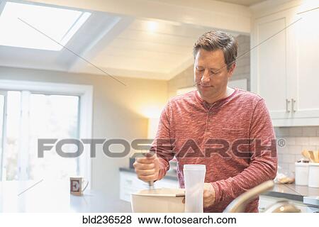Stock Photo - Caucasian man mixing food in bowl. Fotosearch