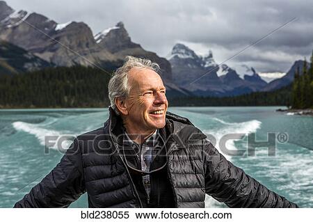 Stock Photography - Caucasian man on boat in mountain lake. Fotosearch