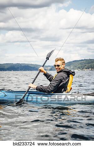 Picture - Caucasian man paddling kayak. Fotosearch