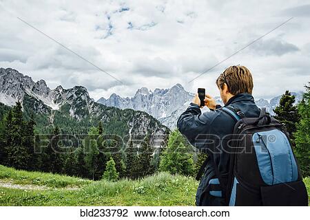 Caucasian man photographing mountain range with cell phone View Large Photo Image Stock Image - Caucasian man photographing mountain range with cell phone. Fotosearch