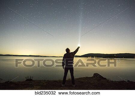 Caucasian man pointing flashlight at night sky near water View Large Photo Image Stock Image - Caucasian man pointing flashlight at night sky near water. Fotosearch