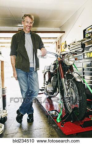 Caucasian man posing with motorcycle in garage View Large Photo Image Stock Image - Caucasian man posing with motorcycle in garage. Fotosearch