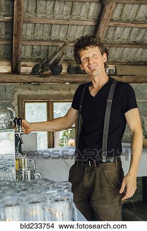 Picture - Caucasian man pouring beer into glass at restaurant. Fotosearch