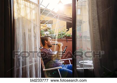 Stock Photo - Caucasian man reading digital tablet drinking red wine. Fotosearch