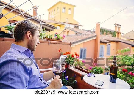 Caucasian man reading digital tablet drinking red wine View Large Photo Image Stock Photo - Caucasian man reading digital tablet drinking red wine. Fotosearch