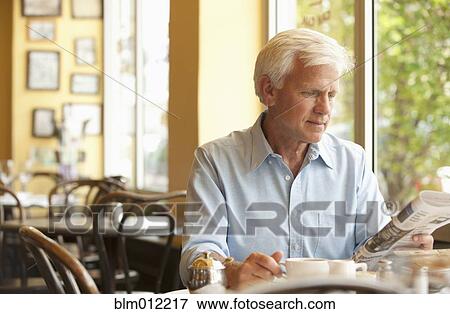 Caucasian man reading newspaper in restaurant View Large Photo Image Stock Photo - Caucasian man reading newspaper in restaurant. Fotosearch