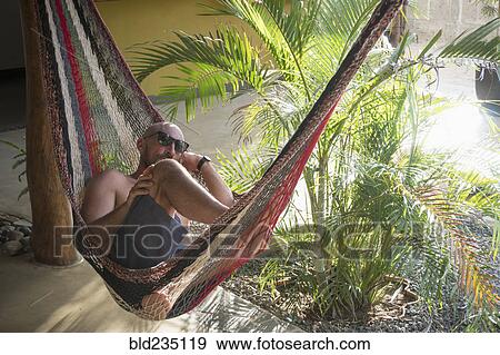 Caucasian man relaxing in hammock View Large Photo Image Stock Photo - Caucasian man relaxing in hammock. Fotosearch