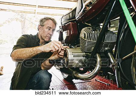 Caucasian man repairing motorcycle in garage View Large Photo Image Stock Image - Caucasian man repairing motorcycle in garage. Fotosearch
