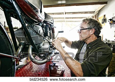 Caucasian man repairing motorcycle in garage View Large Photo Image Stock Photograph - Caucasian man repairing motorcycle in garage. Fotosearch