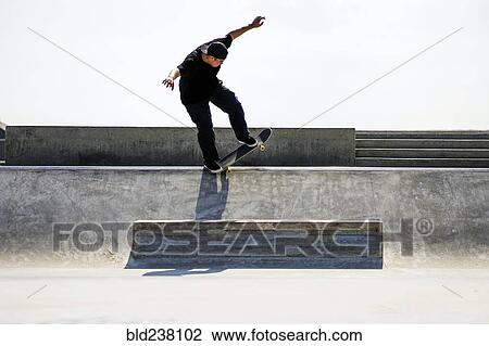 Stock Image - Caucasian man riding skateboard in skate park. Fotosearch