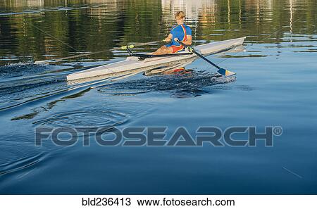 Stock Image - Caucasian man rowing on river. Fotosearch