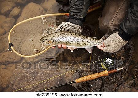 Stock Photography - Caucasian man showing caught fish. Fotosearch