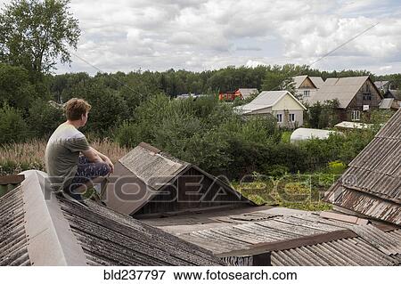 Stock Photo - Caucasian man sitting on roof holding book. Fotosearch