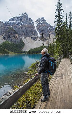 Caucasian man standing on boardwalk admiring mountain View Large Photo Image Stock Photo - Caucasian man standing on boardwalk admiring mountain. Fotosearch