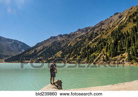 Caucasian man standing on rock near mountain lake View Large Photo Image Stock Image - Caucasian man standing on rock near mountain lake. Fotosearch