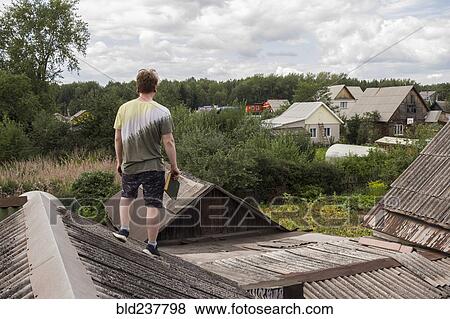 Stock Photo - Caucasian man standing on roof holding book. Fotosearch