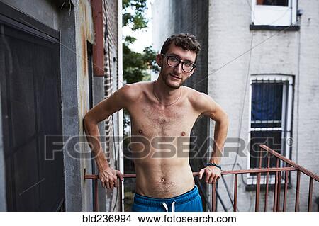 Picture - Caucasian man standing on urban fire escape. Fotosearch
