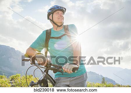 Stock Photo - Caucasian man standing with mountain bike. Fotosearch