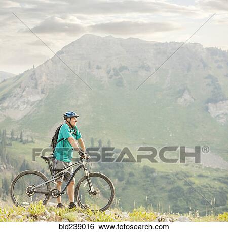 Stock Photograph - Caucasian man standing with mountain bike. Fotosearch