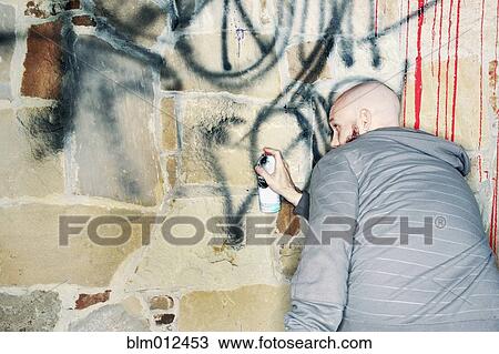 Stock Image - Caucasian man tagging wall with graffiti. Fotosearch