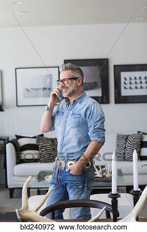 Caucasian man talking on cell phone in livingroom View Large Photo Image Stock Image - Caucasian man talking on cell phone in livingroom. Fotosearch