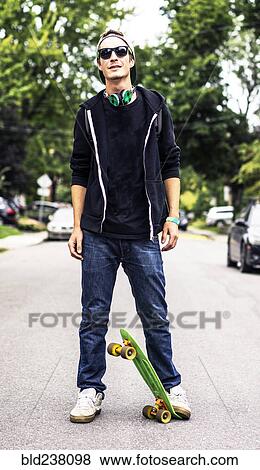 Stock Photo - Caucasian man with headphones standing on skateboard. Fotosearch