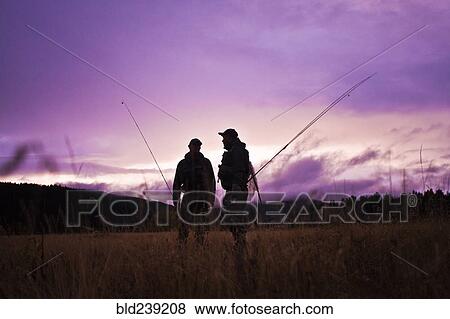 Stock Photo - Caucasian men carrying fishing rods. Fotosearch