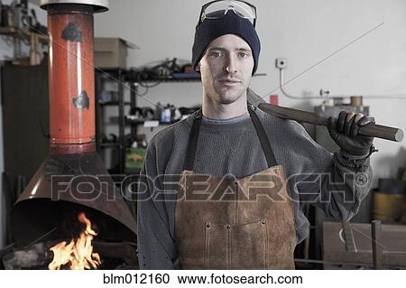 Stock Image - Caucasian metal worker standing in workshop. Fotosearch