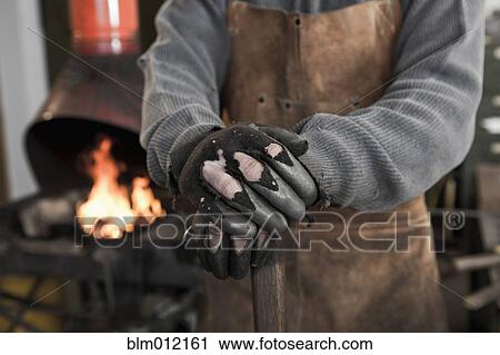 Stock Image - Caucasian metal worker standing in workshop. Fotosearch