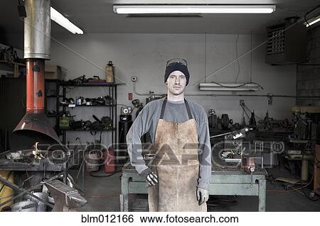 Stock Photograph - Caucasian metal worker standing in workshop. Fotosearch