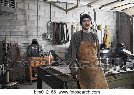 Stock Photography - Caucasian metal worker standing in workshop. Fotosearch