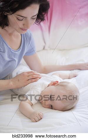 Stock Photo - Caucasian mother and baby son laying on bed. Fotosearch