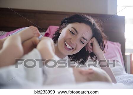 Caucasian mother and baby son laying on bed View Large Photo Image Stock Photo - Caucasian mother and baby son laying on bed. Fotosearch