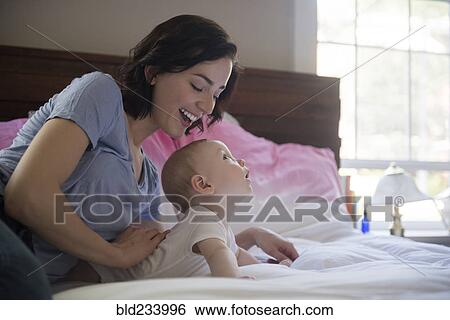 Stock Photograph - Caucasian mother and baby son laying on bed. Fotosearch