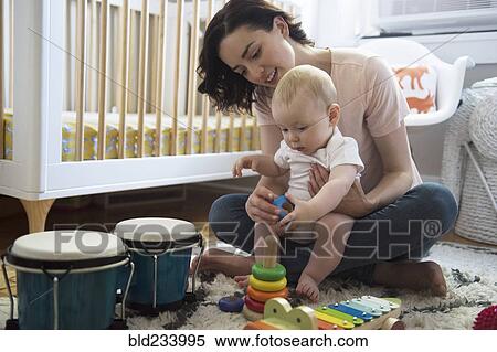 Stock Photography - Caucasian mother and baby son playing with toys on floor. Fotosearch