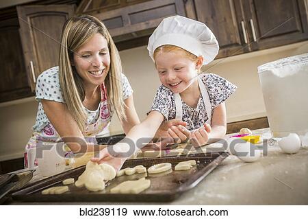 Stock Photo - Caucasian mother and daughter baking cookies. Fotosearch